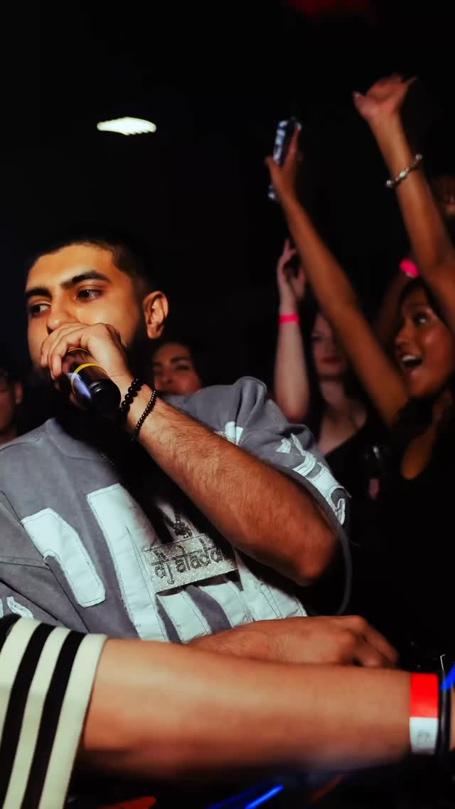 DJ Aladdinn on the mic with a packed crowd cheering with hands up